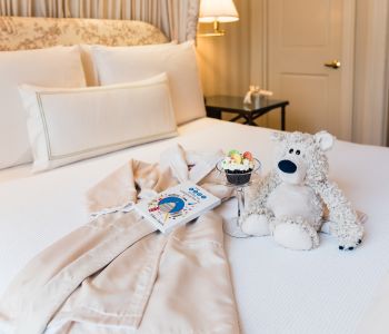 Stuffed Bear, Robe & Toys Spread on Bed at Hay Adams