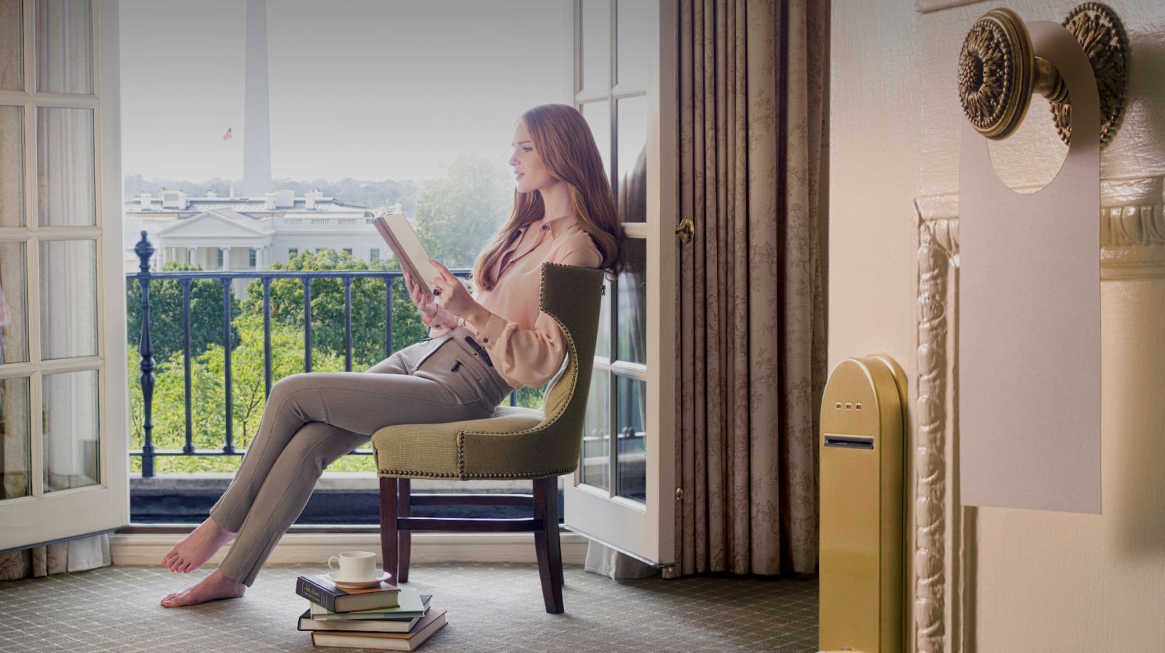 A woman reading a book in a room with a view of the White House at Hay-Adams